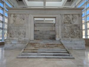 Frontal udsigt over Ara Pacis' indgang med marmortrappen, der fører op til offeralteret, flankeret af mytologiske relieffpaneler