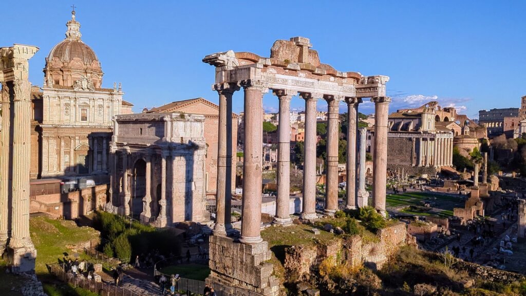lose-up view of the Temple of Saturn's columns in the Roman Forum, with Santi Luca e Martina church dome in the background