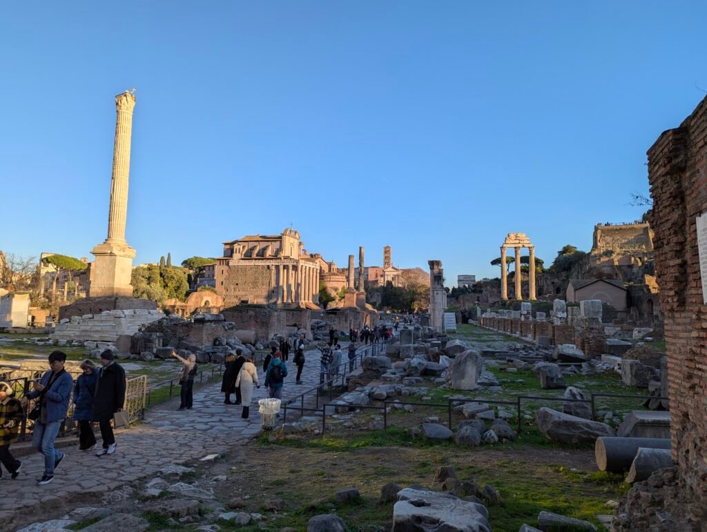 The Via Sacra ancient road through the Roman Forum at sunset, with the Column of Phocas and Temple of Saturn's columns visible