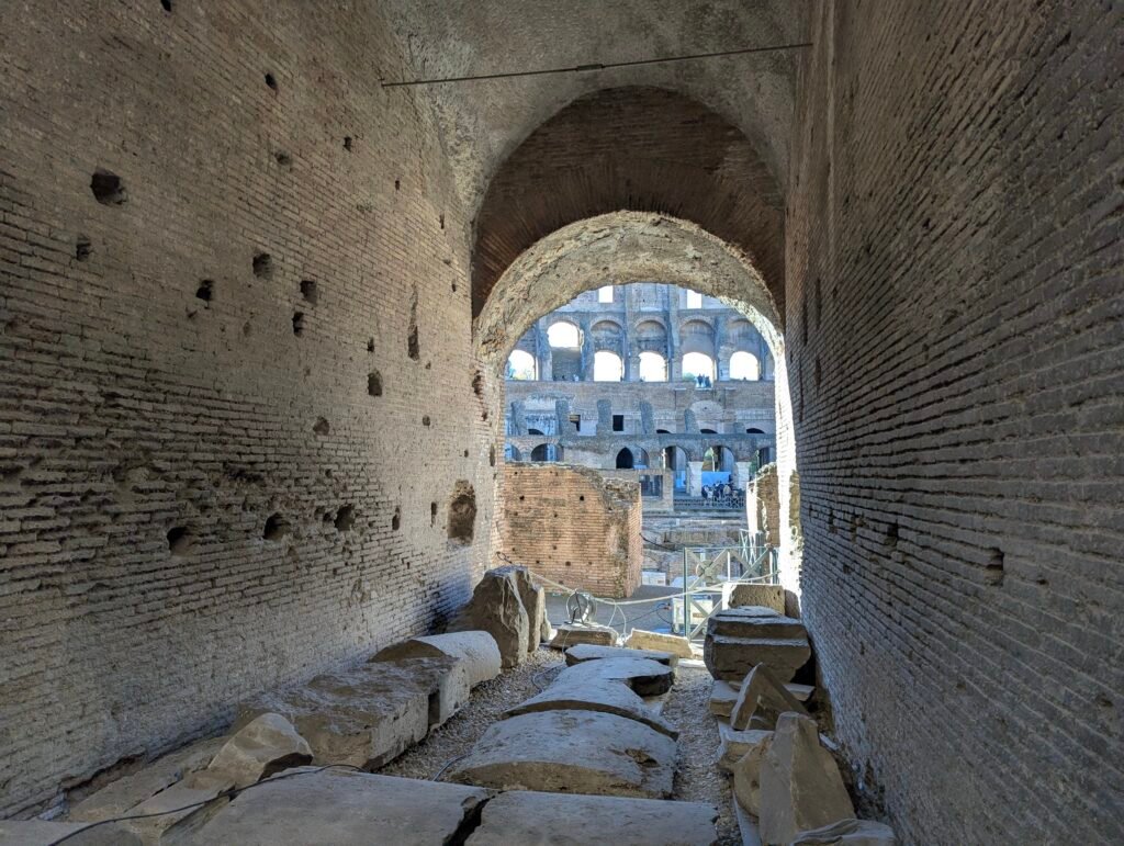 Antikk teglkorridor inne i Colosseum som rammer inn utsikten mot arenaen gjennom et hvelv