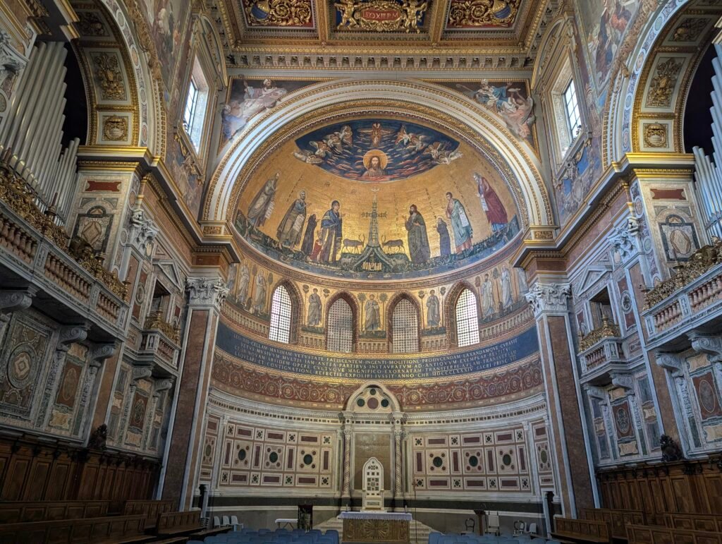Utsikt over den storslåtte apsismosaikken og det dekorerte taket inne i San Giovanni in Laterano-basilikaen i Roma, med gullfarget Bysantin-inspirert kunst og pavekatedraen.