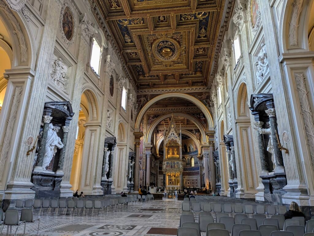 Innvendig utsikt over hovedskipet i San Giovanni in Laterano-basilikaen i Roma, mot pavealteret under et fantastisk forgylt kassetttak.